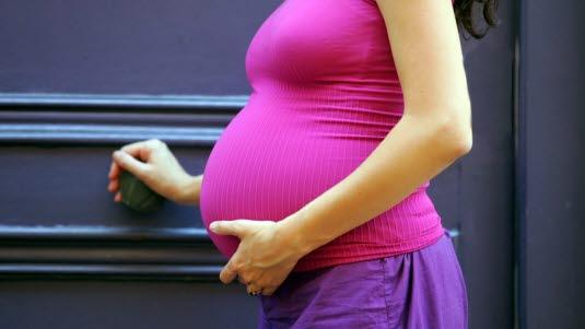 Illustrasjonsfoto av en gravid mage sett fra siden. Kvinnen har på seg en lilla singlet