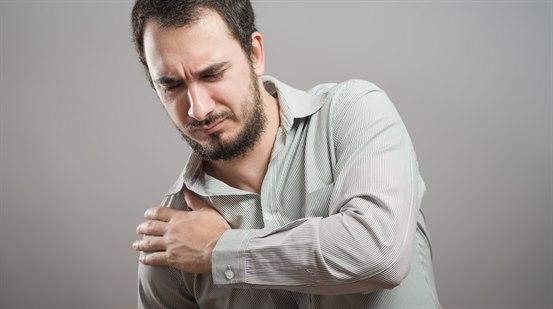 Ung mann som holder seg til smertefull høyre skulder.