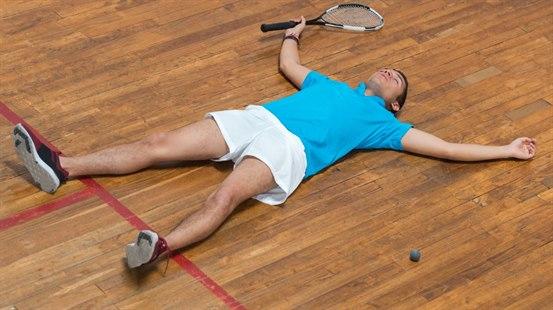 Tennisspiller som ligger urørlig på gulvet.