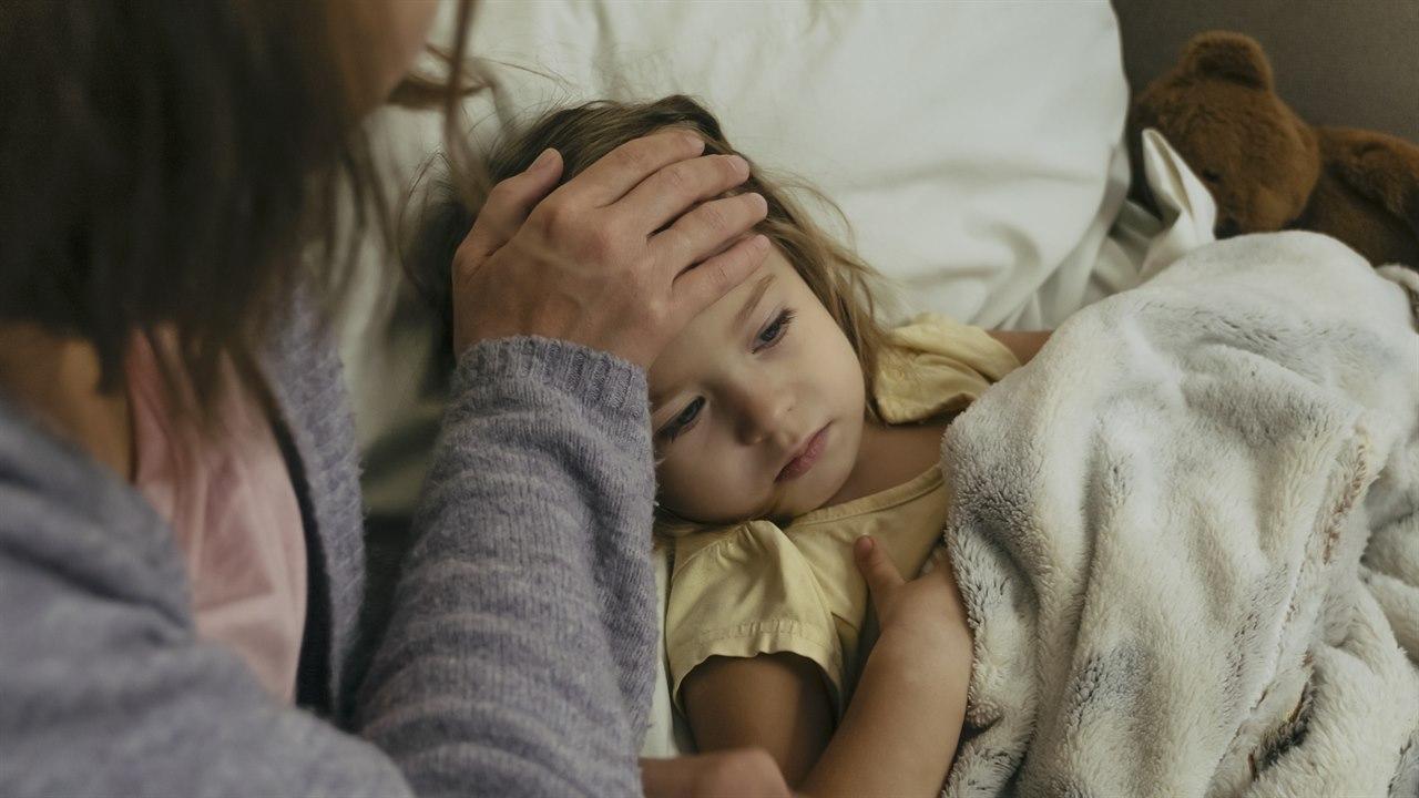 Illustrasjonsfotoet viser et bilde av et barn som ligger i senga der mor sjekker feber i pannen 