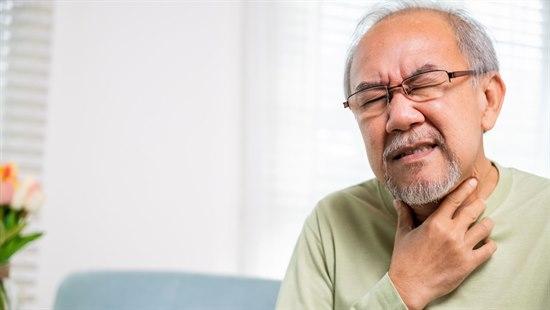 Person som tar seg til halsen. Ansiktet gir uttrykk for ubehag.