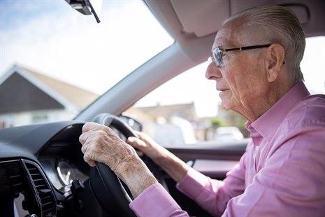 Fotoet viser en gammel mann som kjører bil, virker anspent og noe engstelig. 