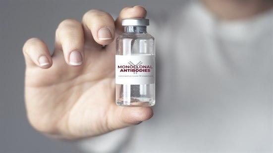 Bilde av en hånd som holder et medisinglass med påskriften "monoclonal antibodies".