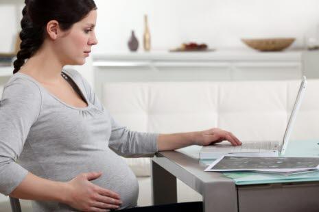 Illustrasjonsfotoet viser en gravid kvinne som sitter foran en bærbar PC