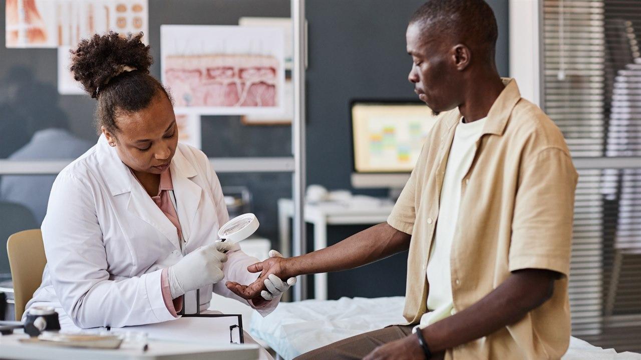 Illustrasjonsfotoet viser lege som undersøker hud på hånd hos pasient 