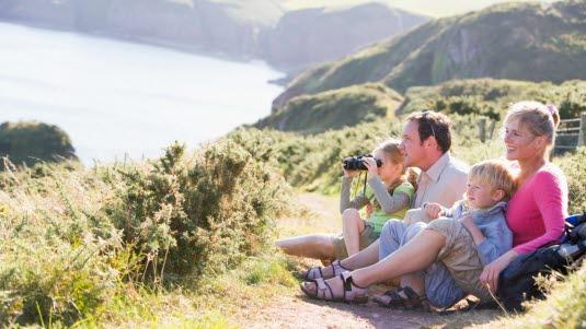 Illustrasjonsfoto av en familie på fire, som sitter i en sti og ser ut mot fjorden.