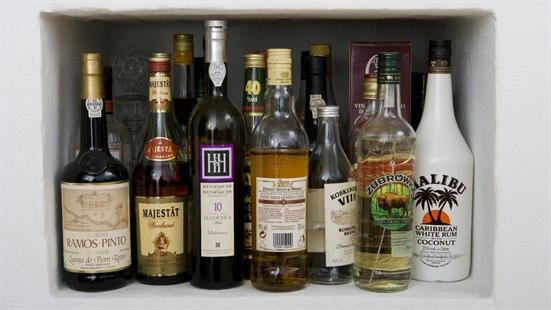 Mange ulike flasker med alkoholholdig drikke plassert i en nisje, likner et barskap. 