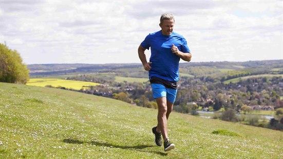 Illustrasjonsfoto: Mann i blå t-skjorte og blå shorts jogger over en gressplen.