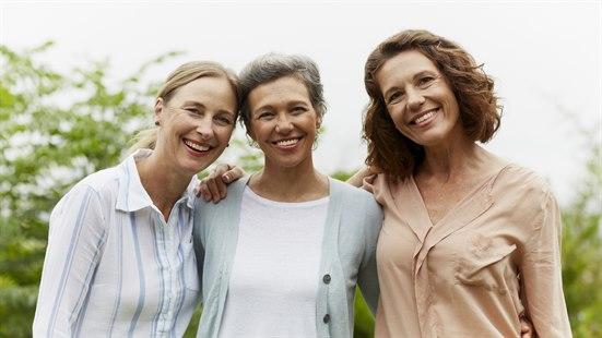 Illustrasjonsfoto av tre kvinner som smiler og holder rundt hverandre