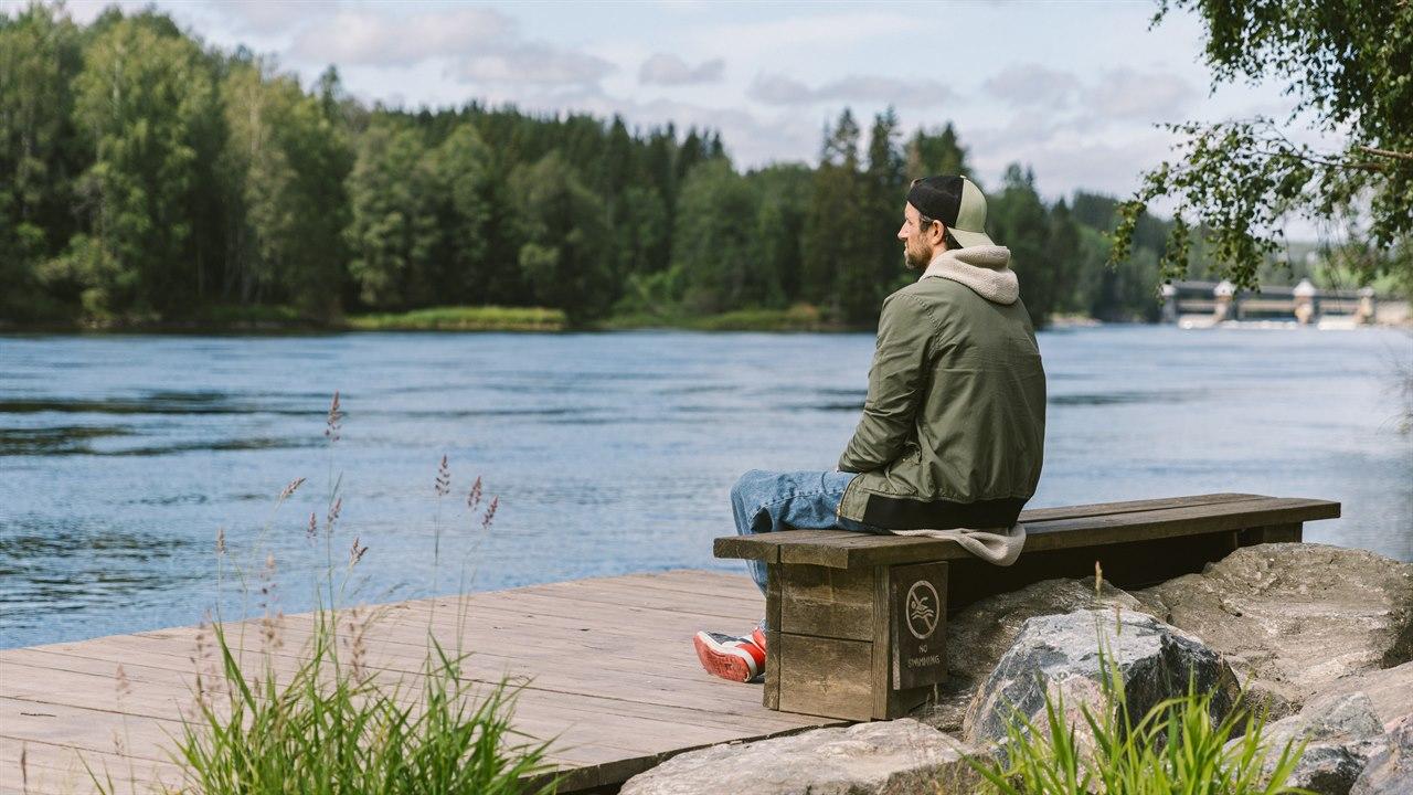 Illustrasjonsfotoet viser mann som sitter på en benk ved en innsjø
