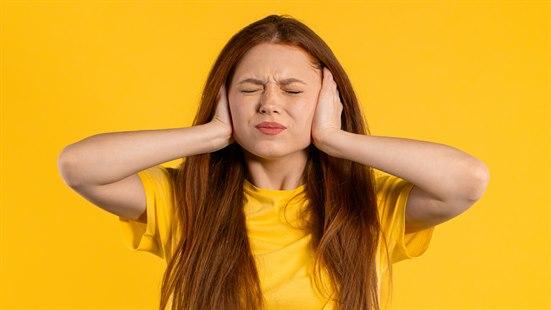 Illustrasjonsfotoet viser en kvinne som holder seg for ørene