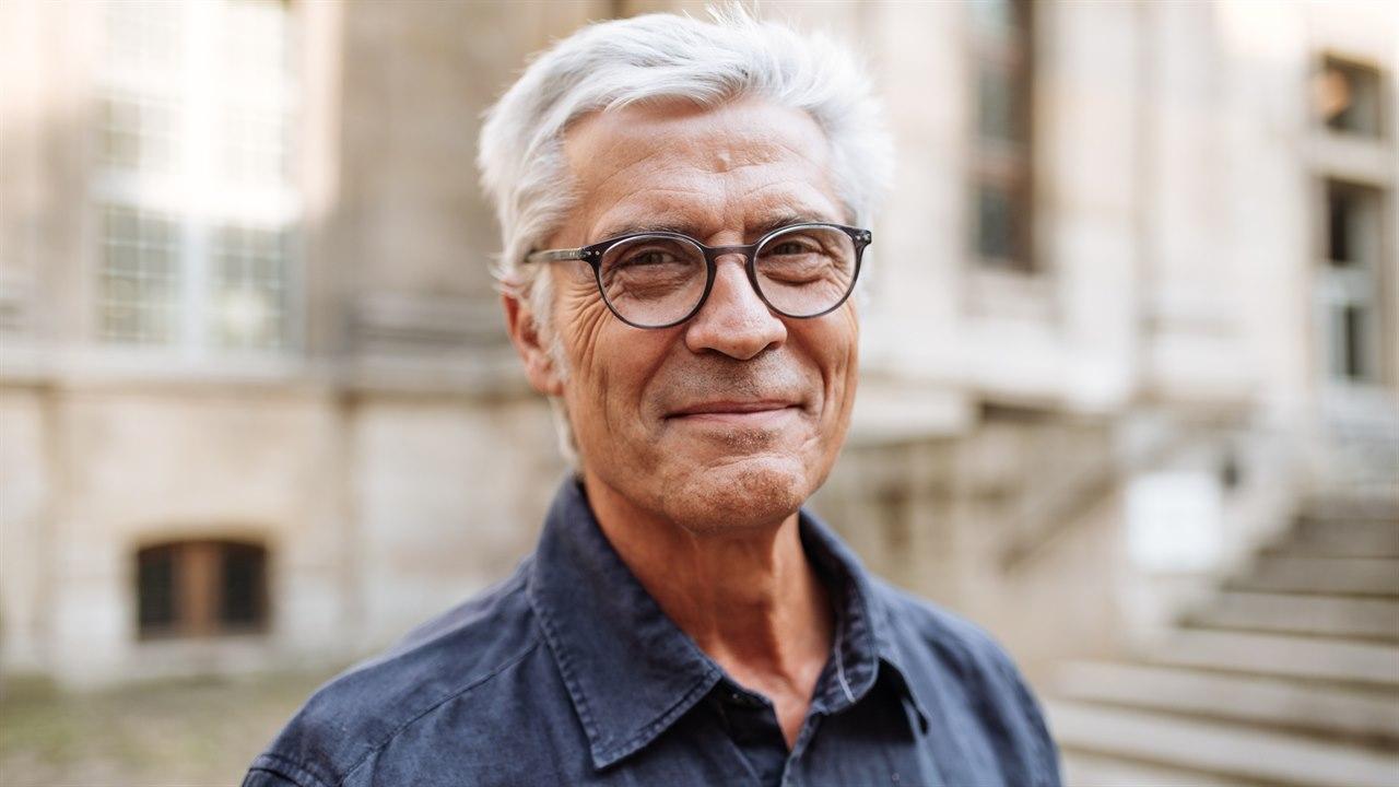 Illustrasjonsfotoet viser en senior mann med briller. Han er utendørs og ser rett i kameraet.