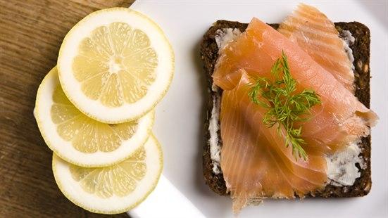 Et illustrasjonsfoto av en laksefilet med tre sitronbåter plassert ved siden av i en rekke.