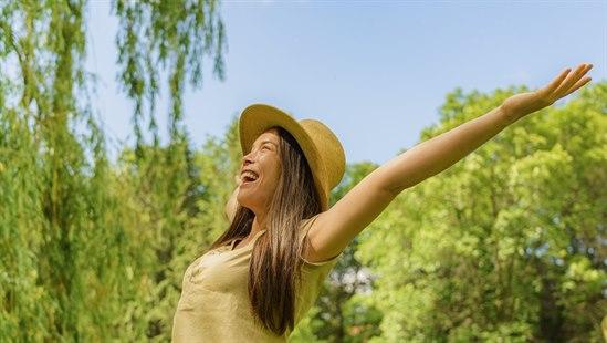 Ung kvinne jublende i bjørkeskog. 