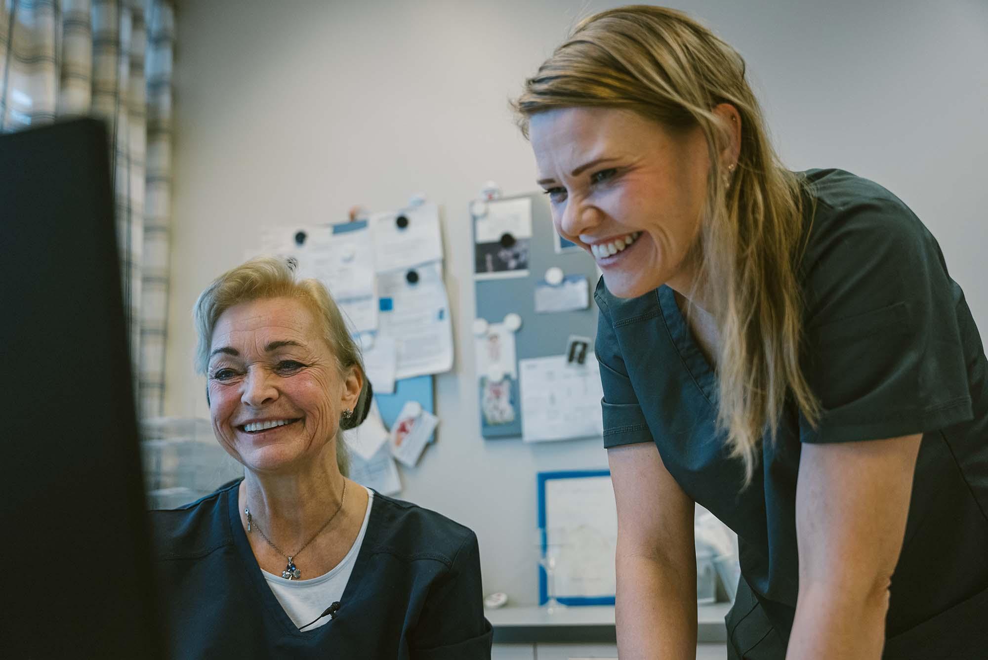 Fotoet viser to leger som smiler mens de ser på en pc-skjerm
