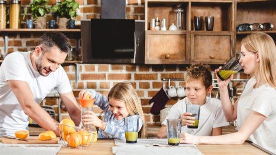 Illustrasjonsfoto av en familie på kjøkkenet som presser apelsinjuice.