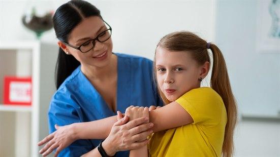 Illustrasjonsfotoet viser ei jente som får hjelp til å tøye i overarmen