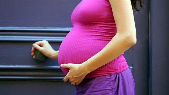 Illustrasjonsfoto av en gravid mage sett fra siden. Kvinnen har på seg en lilla singlet