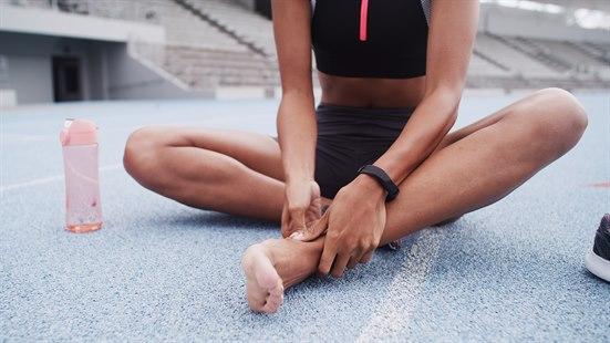 Illustrasjonsfotoet viser en løper som sitter på en friidrettsbane. Løperen tar seg til foten