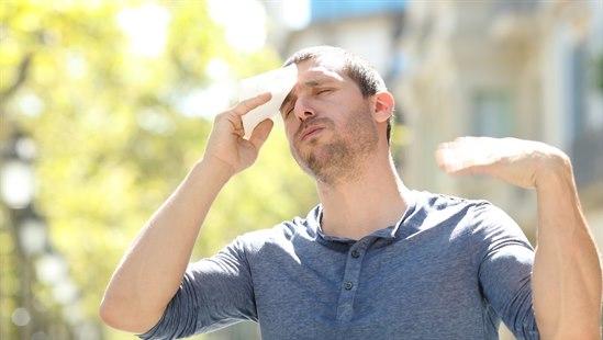 Illustrasjonsfoto av mann i friluft plaget av varmt vær og tørker panna med et papirtørk