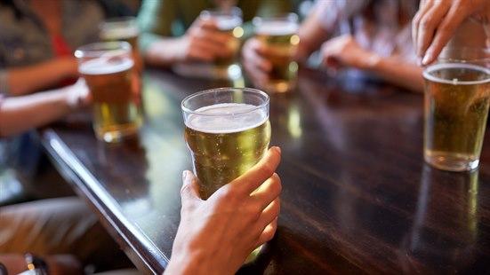 Illustrasjonsfotoet viser flere ølglass og hendene til personer som sitter rundt et bord