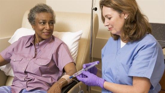 Illustrasjonsfotoet viser en kvinne som sitter i en stol og får en injeksjon av en kvinnelig sykepleier