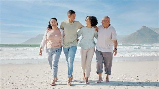 Illustrasjonsbilde av to kvinner og to menn som går tett sammen på ei strand en finværsdag.