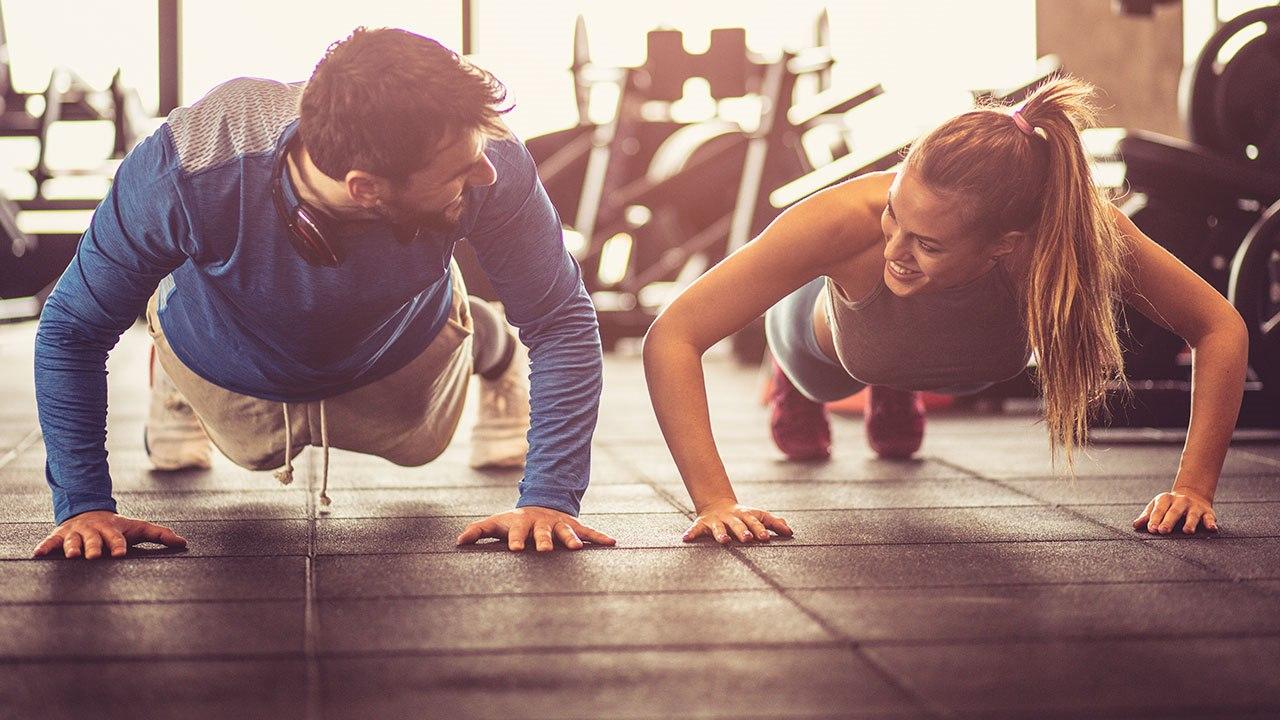 Illustrasjonsfoto av en kvinne og en mann, som trener på et treningsstudio. Begge gjennomfører push-up øvelsen.