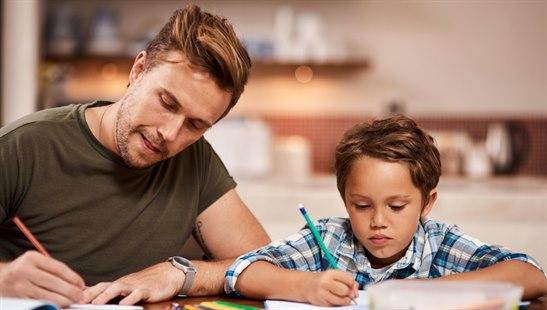 Illustration photo of a father teaching boy at table writing