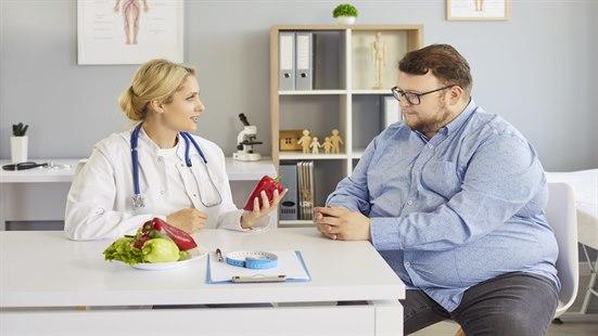 Bilde av sterkt overvektig ung mann som får råd fra kvinnelig lege.