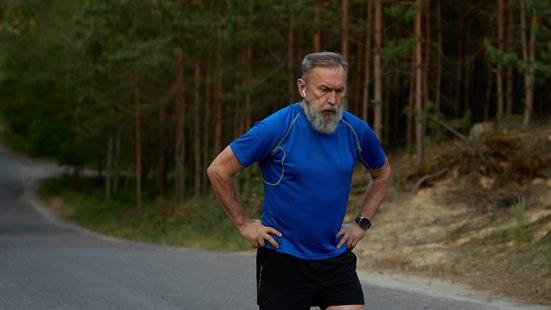 Illustrasjonsfoto av sliten, eldre mann med løpeklær. Skog i bakgrunnen.